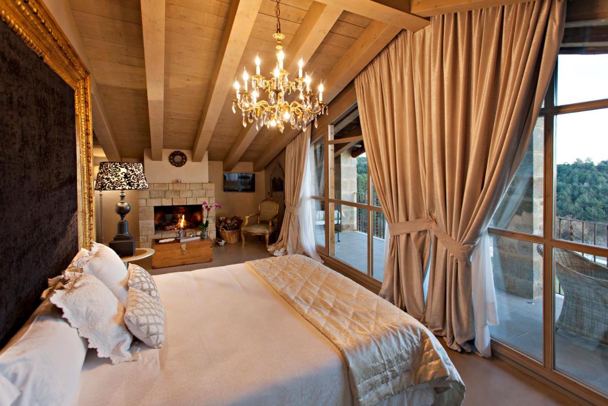 1 dormitorio con 1 cama con lámpara de araña y chimenea en La Vella Farga Hotel, en Lladurs 62 fotos más