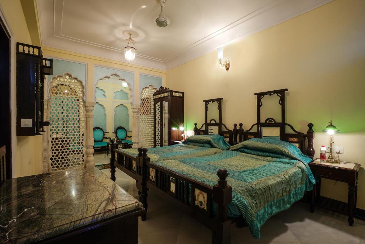 a bedroom with a bed with a green comforter at Shahpura House in Jaipur