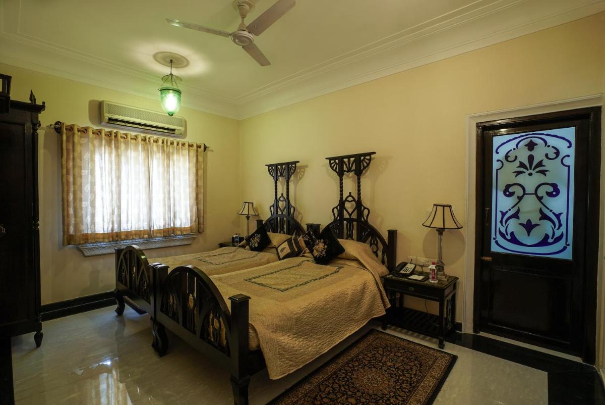 a bedroom with two beds and a ceiling fan at Shahpura House in Jaipur