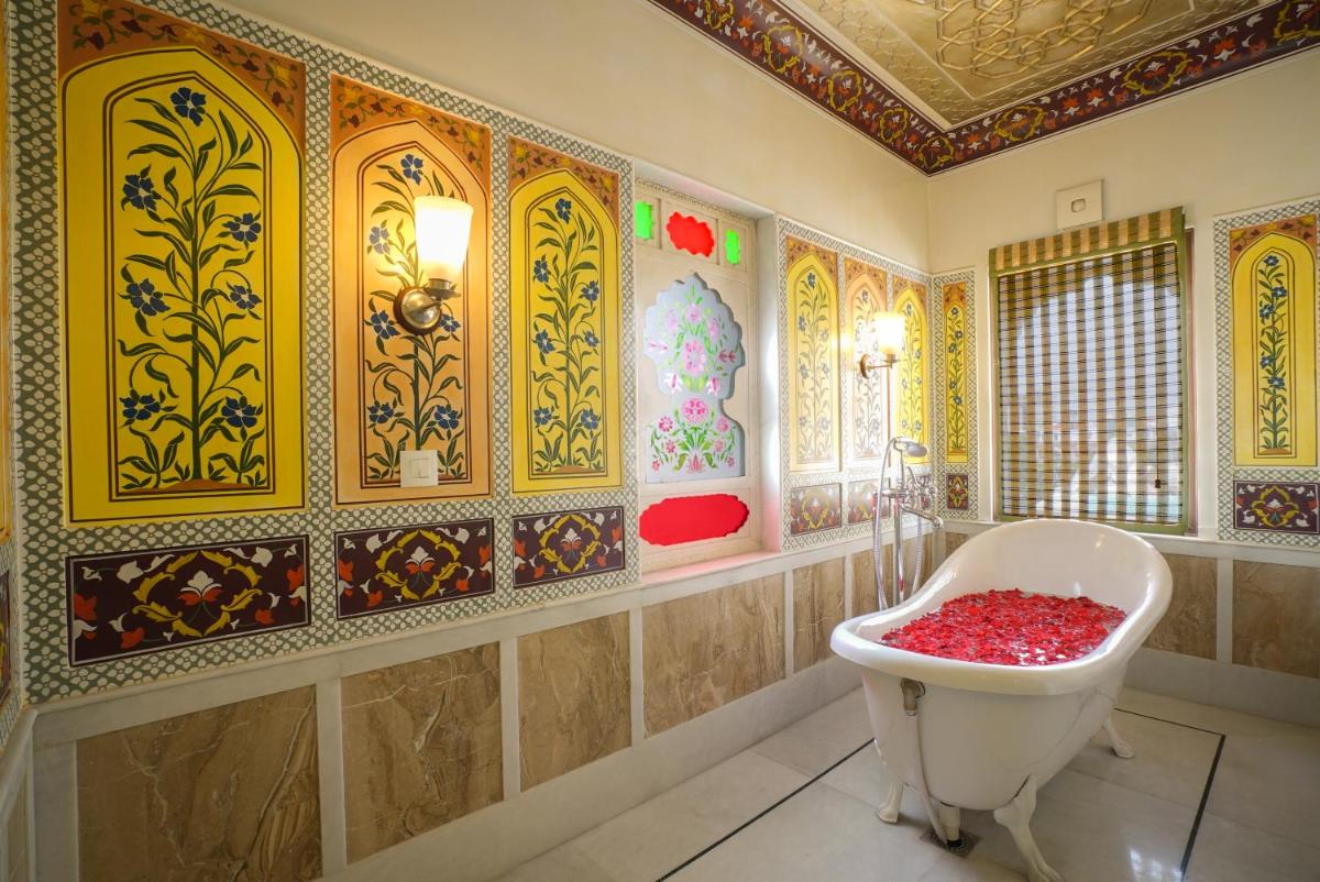 a bathroom with a tub and a decorated wall at Shahpura House in Jaipur