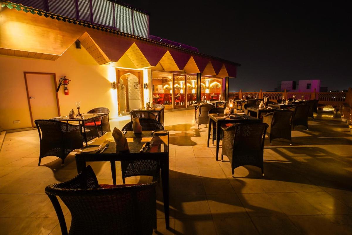 a row of tables and chairs on a patio at night at Shahpura House in Jaipur