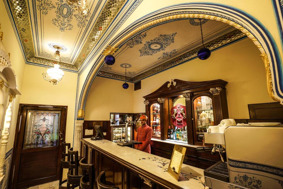 a man standing at a bar in a room with a mirror at Shahpura House in Jaipur