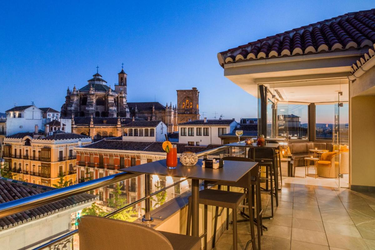 Un balcón con mesas y sillas y vista a la ciudad. en Eurostars Gran Via, en Granada