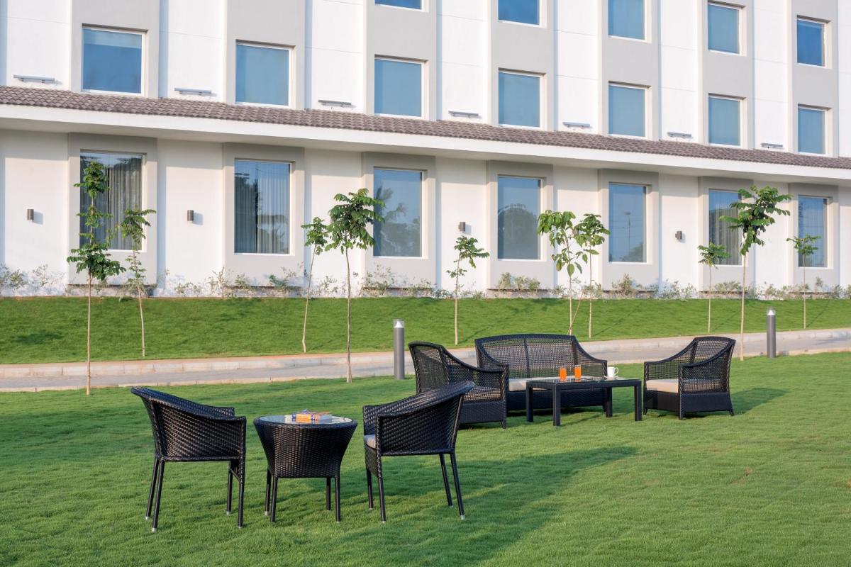 a group of chairs and tables on a lawn in front of a building at The Residency Towers, Rameswaram in Rāmeswaram