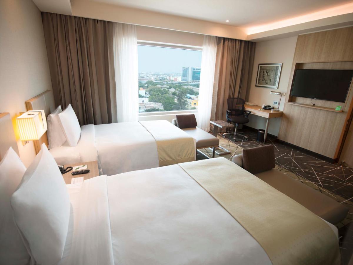 a hotel room with two beds and a flat screen tv at Holiday Inn Chennai OMR IT Expressway by IHG in Chennai