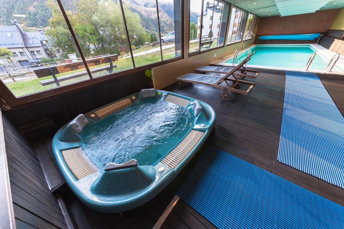 bañera de hidromasaje en una habitación con piscina en Aparthotel Sarrato, en Sallent de Gállego