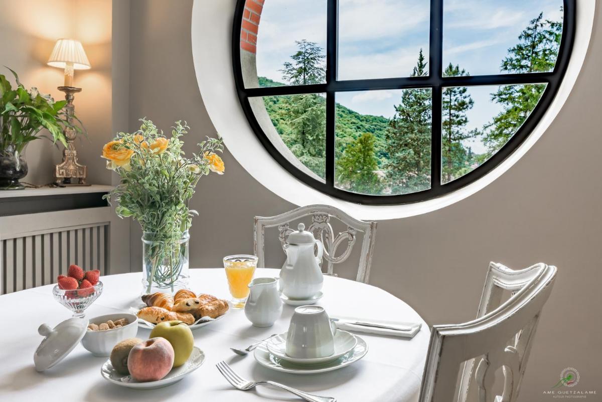 une table avec une assiette de nourriture et une fenêtre ronde dans l'établissement Hôtel Restaurant Spa Le Sauvage, à Besançon