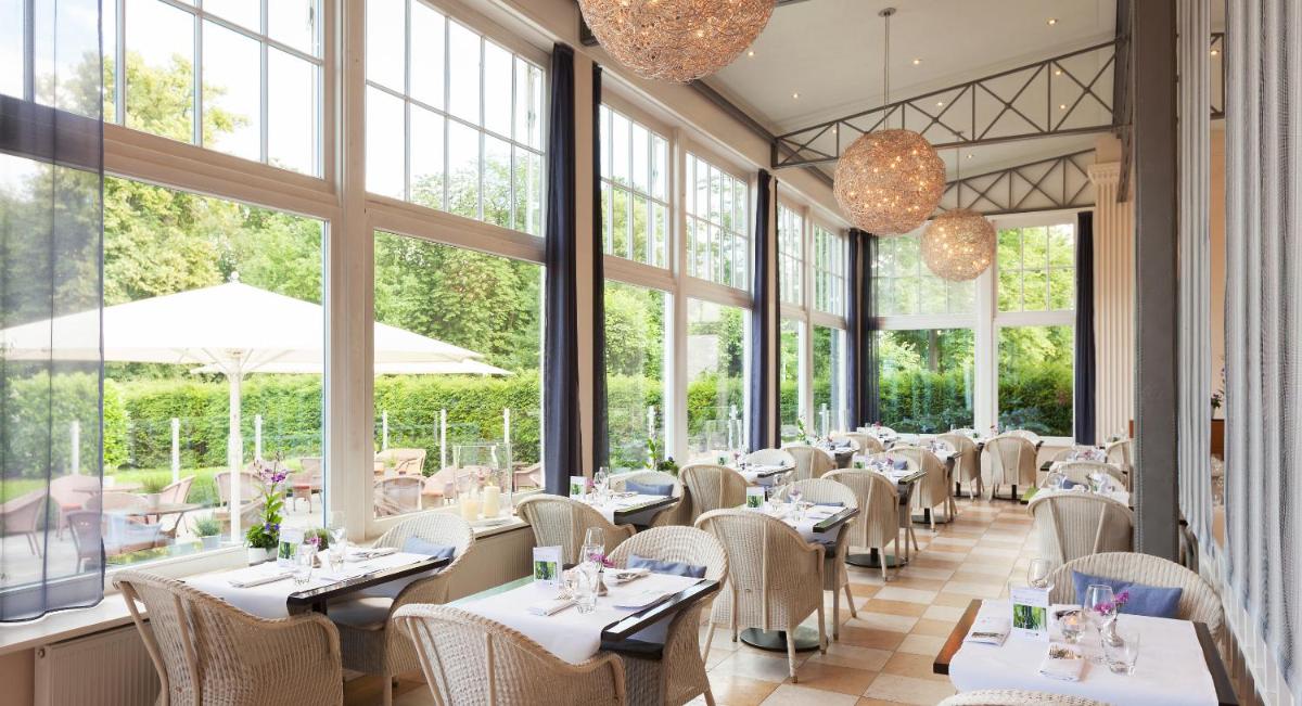 ein Restaurant mit Tischen und Stühlen und Fenstern in der Unterkunft A-ROSA Travemünde in Travemünde