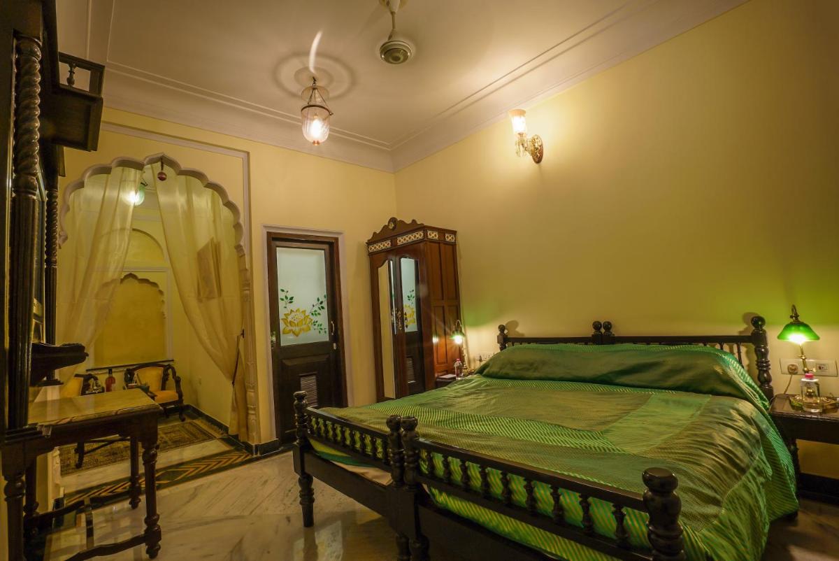 a bedroom with a green bed and a mirror at Shahpura House in Jaipur