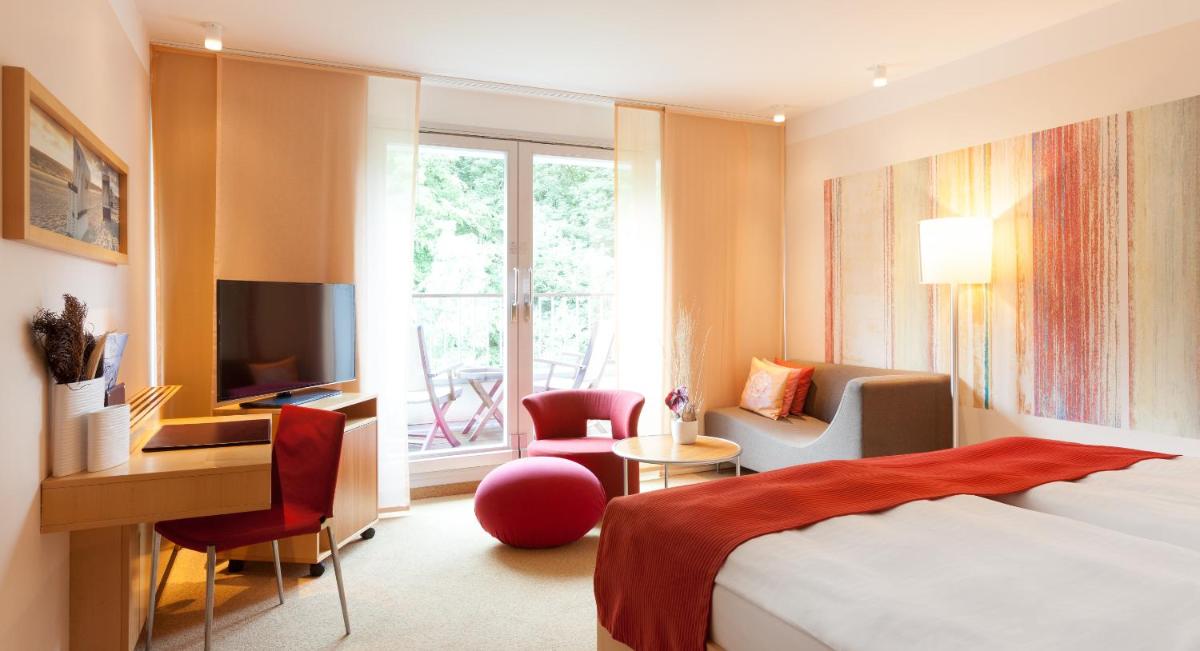 ein Hotelzimmer mit einem Bett, einem Schreibtisch und einem Fenster in der Unterkunft A-ROSA Travemünde in Travemünde