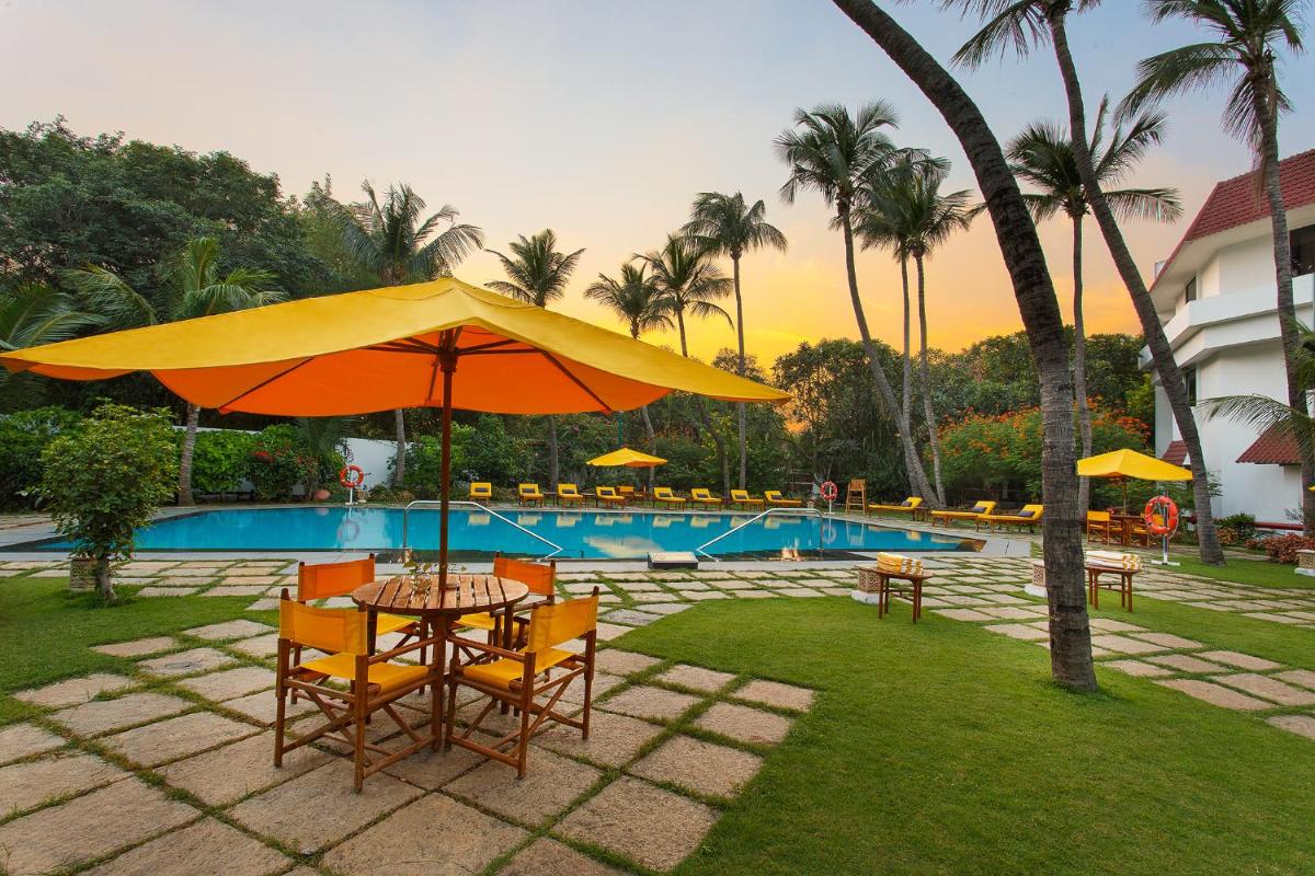 a table and chairs with an umbrella next to a pool at Trident Chennai in Chennai