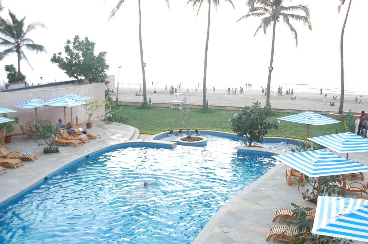 a swimming pool with chairs and umbrellas at a resort at Sun-n-Sand Mumbai Juhu Beach in Mumbai
