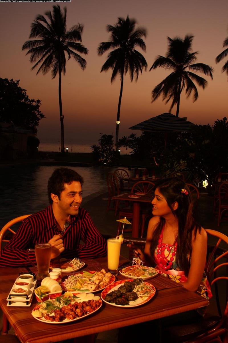 a man and woman sitting at a table with plates of food at Sun-n-Sand Mumbai Juhu Beach in Mumbai