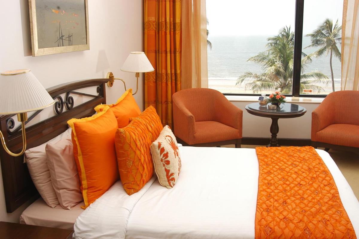 a bedroom with a bed with orange pillows and a window at Sun-n-Sand Mumbai Juhu Beach in Mumbai