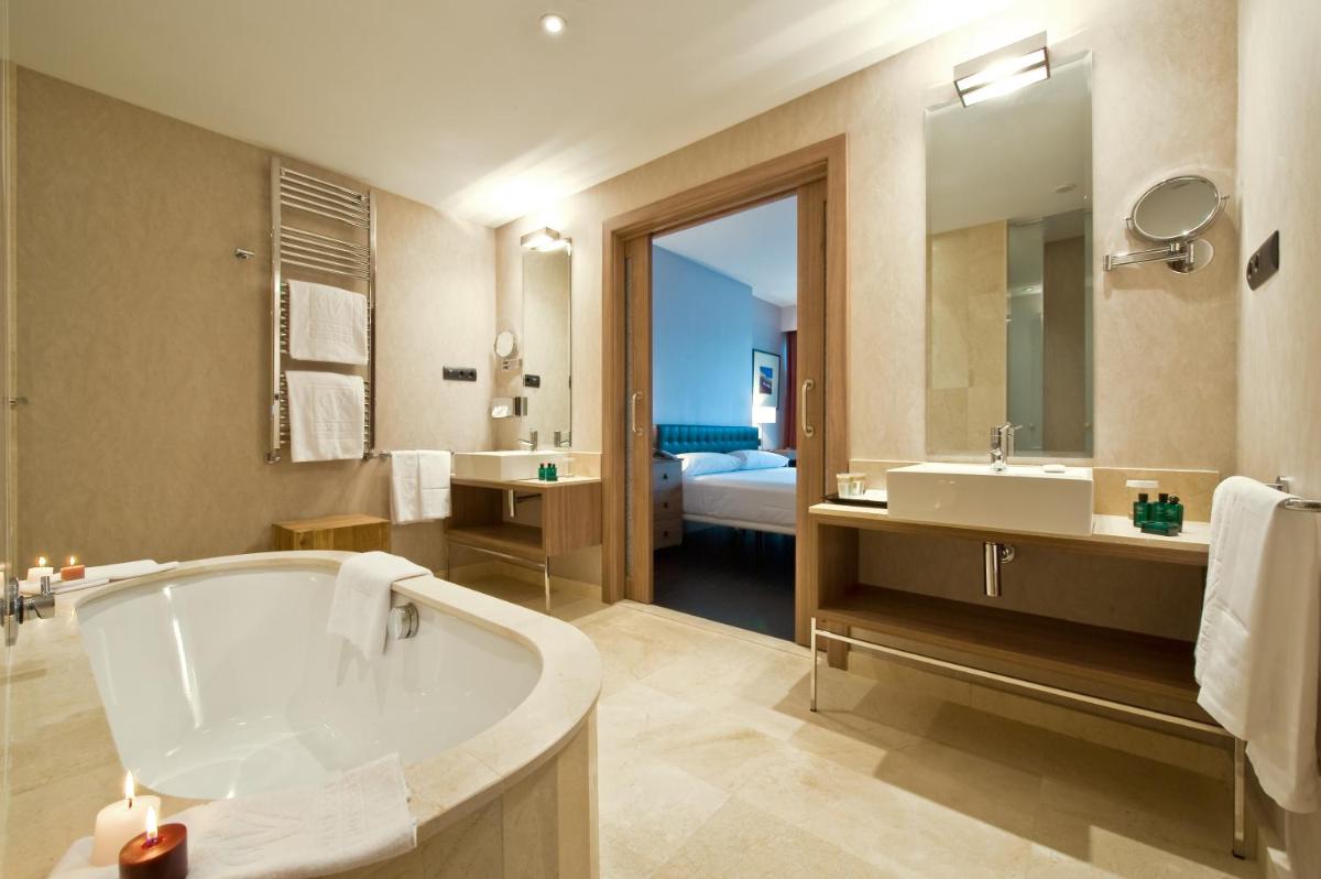 Un baño con bañera, lavabo y cama. en URH Hotel Spa Zen Balagares, en Overo