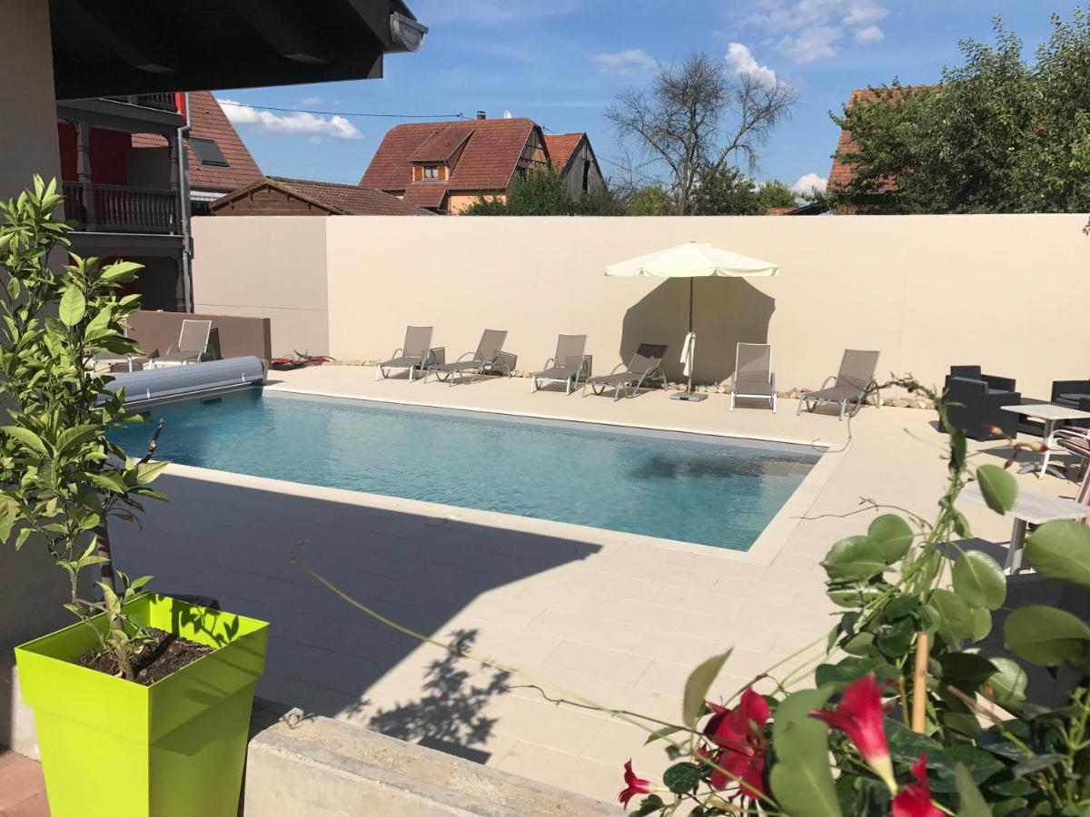 une piscine avec des chaises et un parasol dans l'établissement Au Soleil, Hôtel Restaurant & Spa, à Valff