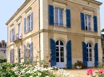 une maison avec des volets bleus et des fleurs devant elle dans l'établissement Logis Le Parc Hotel & Spa, à Château-Gontier