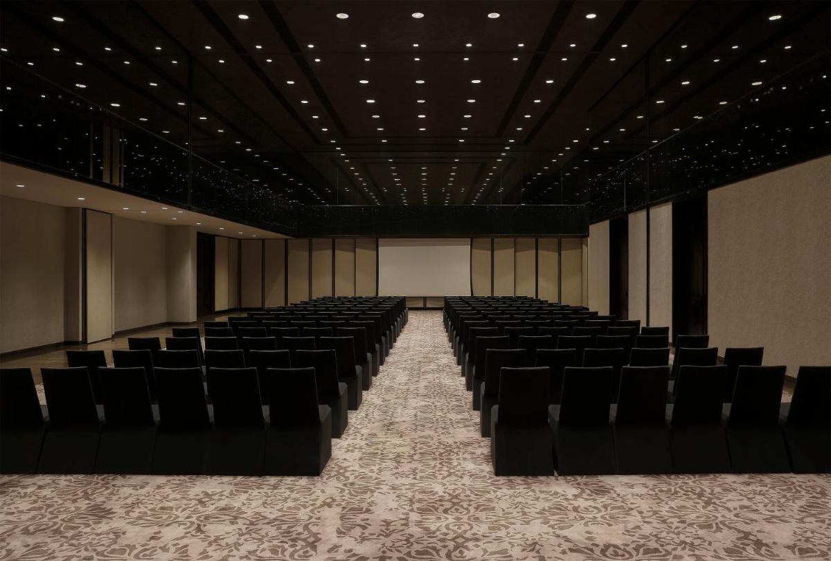 an empty auditorium with black chairs in a room at Roseate House New Delhi in New Delhi an empty auditorium with black chairs in a room at Roseate House New Delhi in New Delhi