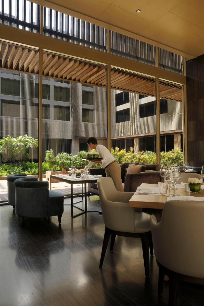 a woman sitting at a table in a restaurant at Roseate House New Delhi in New Delhi a woman sitting at a table in a restaurant at Roseate House New Delhi in New Delhi