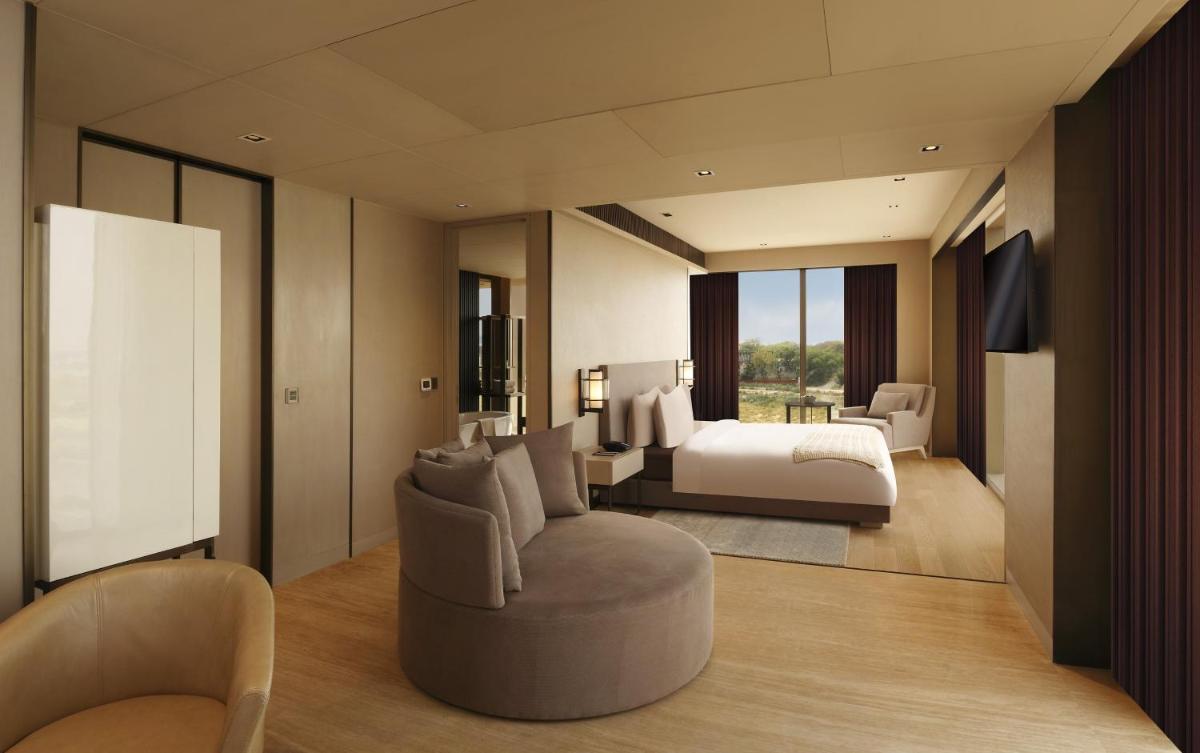 a bedroom with a bed and a couch and a chair at Roseate House New Delhi in New Delhi a bedroom with a bed and a couch and a chair at Roseate House New Delhi in New Delhi