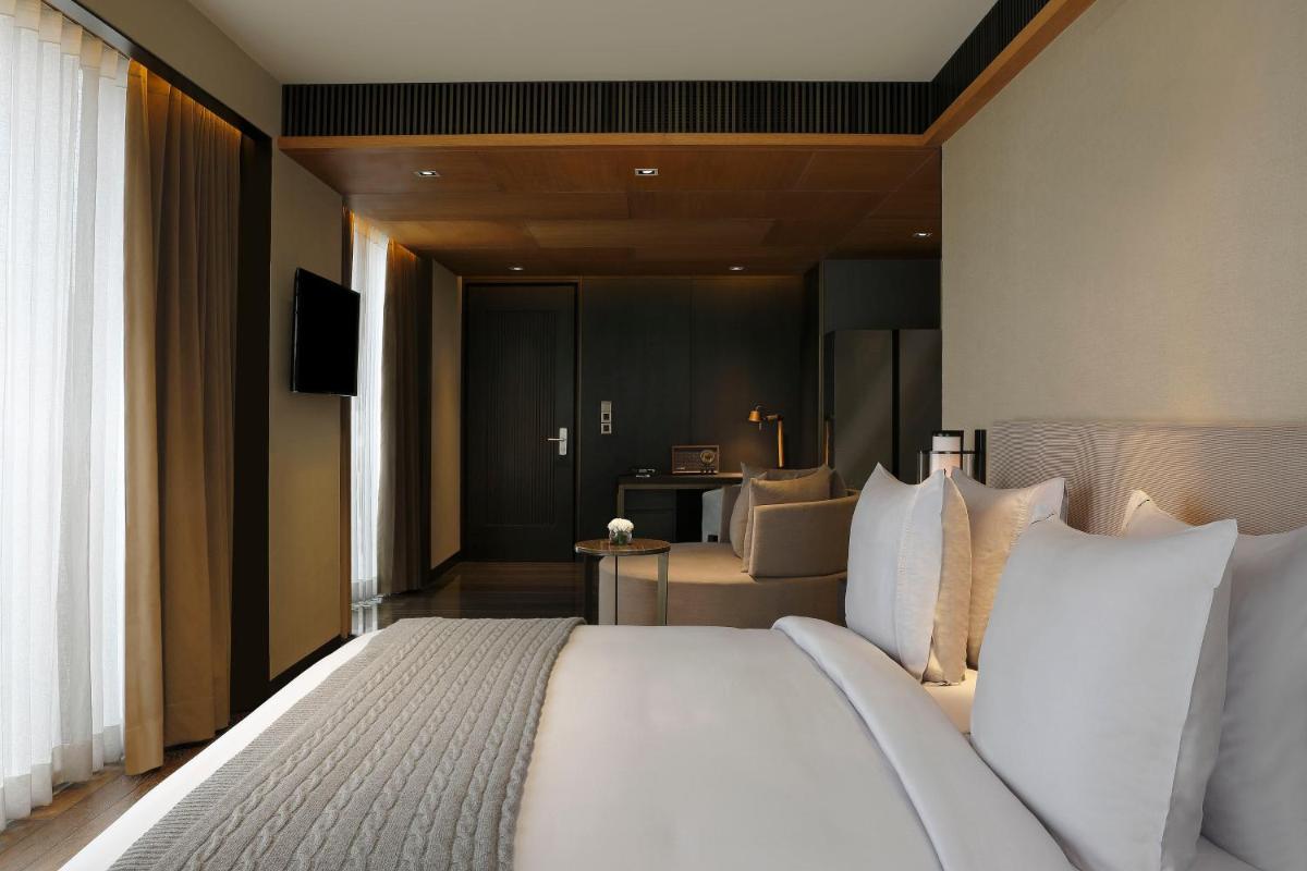 a bedroom with a large white bed and a living room at Roseate House New Delhi in New Delhi a bedroom with a large white bed and a living room at Roseate House New Delhi in New Delhi