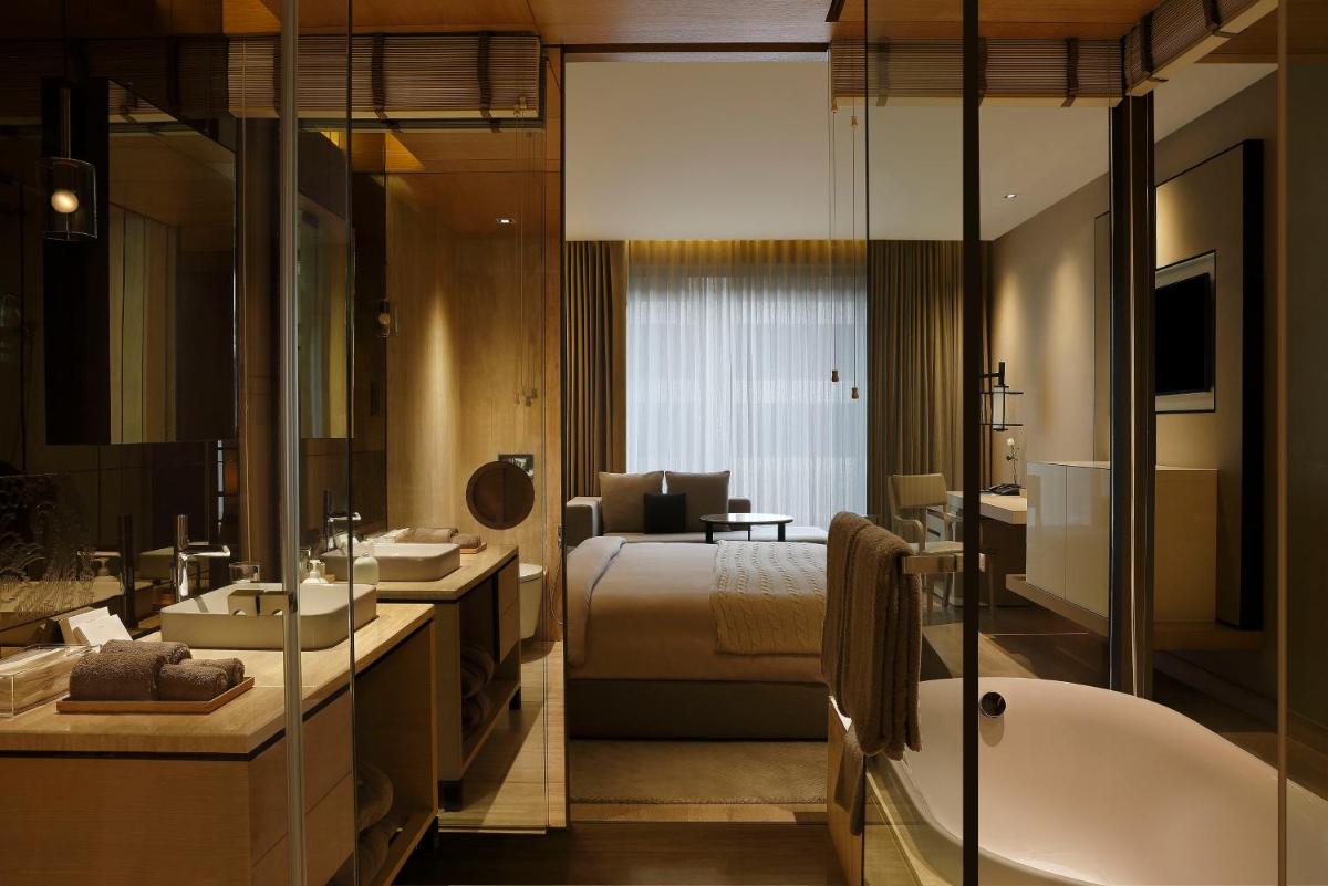 a bathroom with a bed and a tub and a bedroom at Roseate House New Delhi in New Delhi a bathroom with a bed and a tub and a bedroom at Roseate House New Delhi in New Delhi