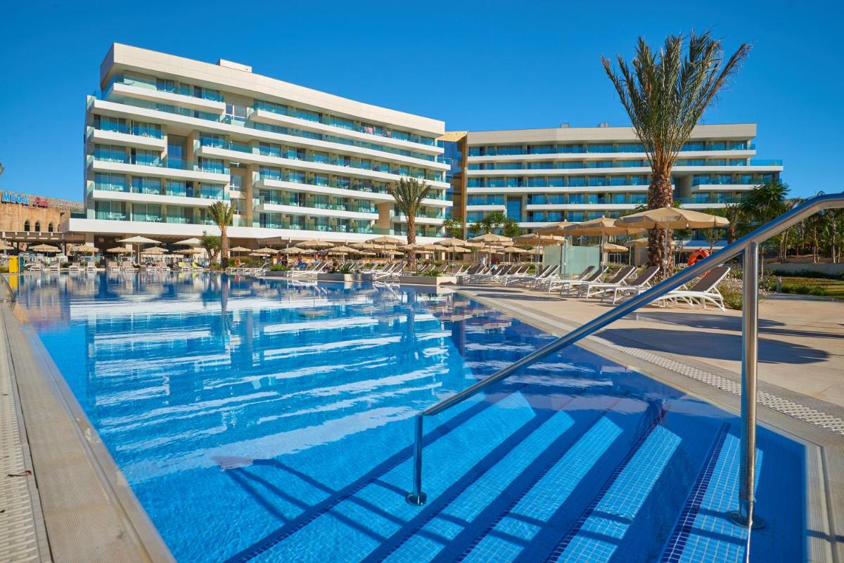 Una gran piscina con sillas y un hotel. en Hipotels Gran Playa de Palma, en Playa de Palma