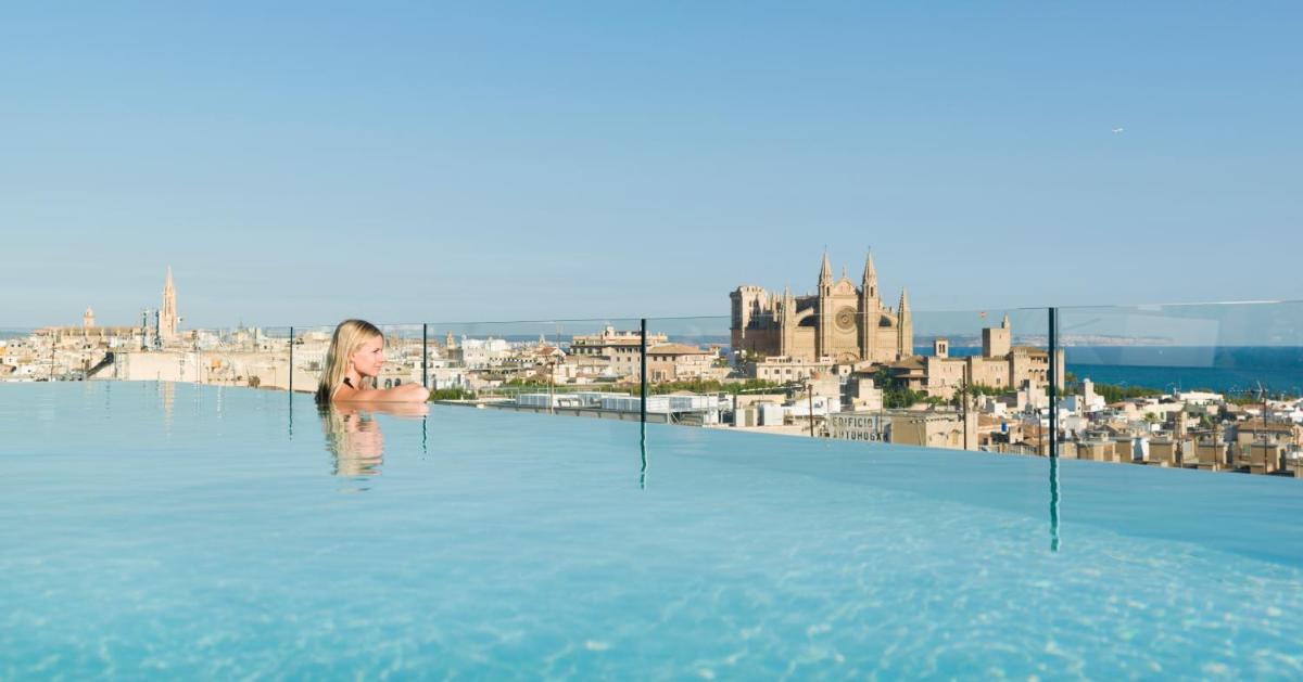 Una mujer en una piscina infinita con una ciudad al fondo. en Nakar Hotel, en Palma de Mallorca