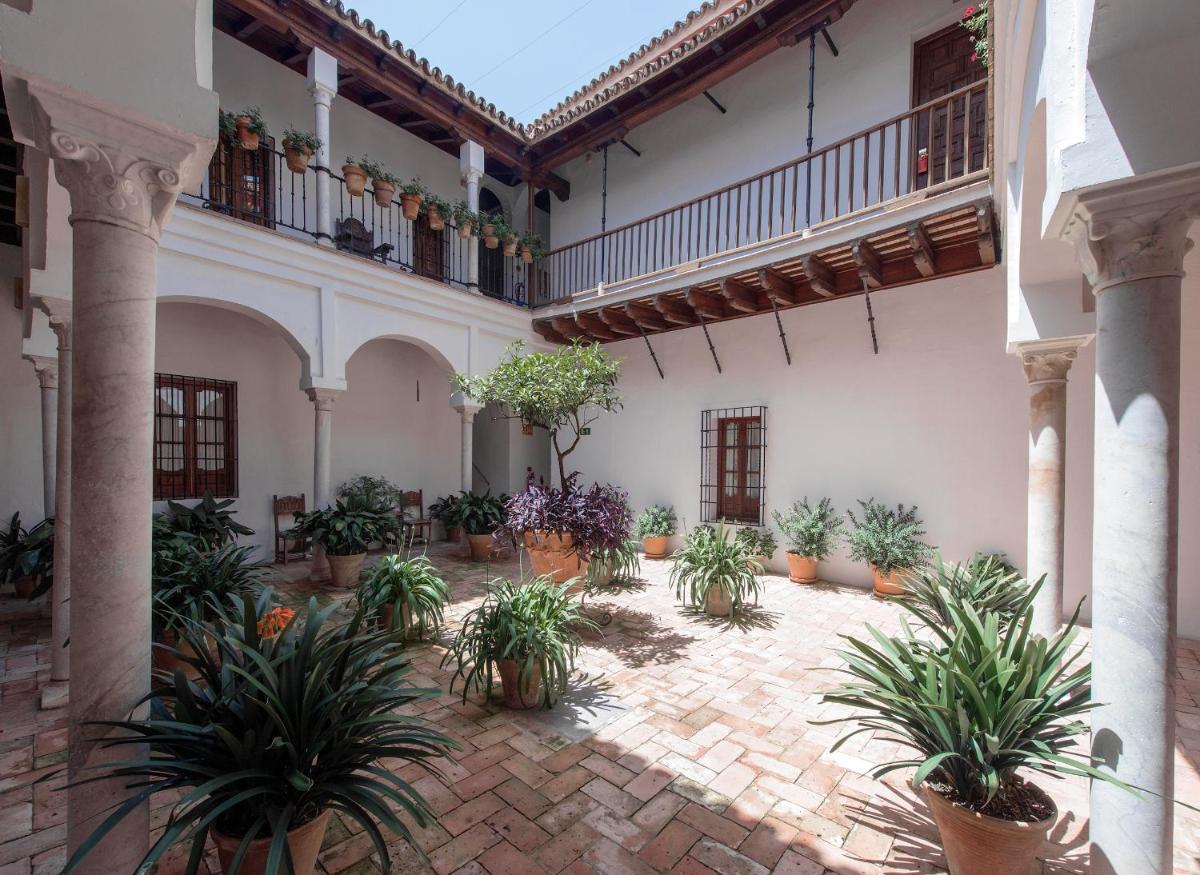 Un patio con plantas en macetas en un edificio. en Hotel Las Casas de la Judería, en Sevilla