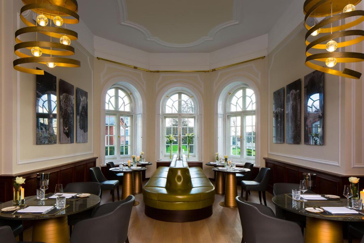 ein Restaurant mit Tischen und Stühlen und Fenstern in der Unterkunft SCHLOSS Fleesensee in Göhren-Lebbin
