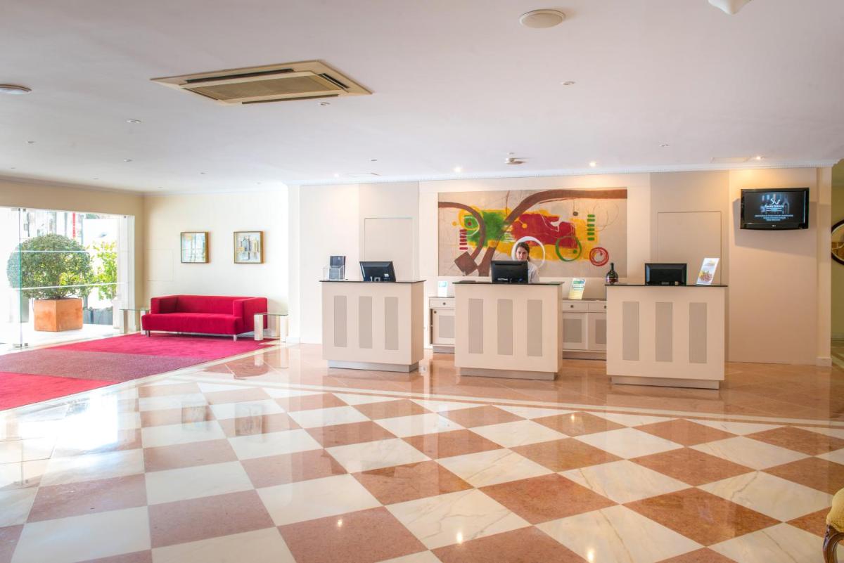um átrio com um piso xadrez e um sofá vermelho em Vila Galé Estoril em Estoril mais 58 fotografias