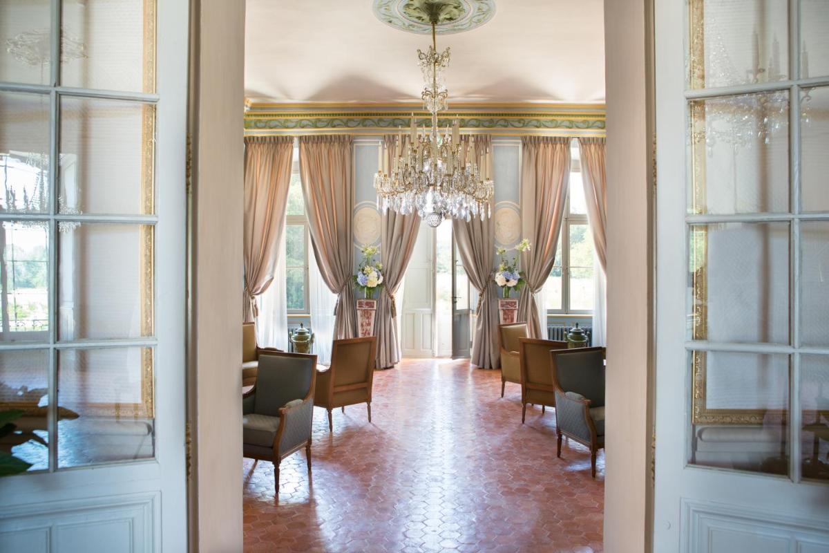 une salle à manger avec une table, des chaises et un lustre dans l'établissement Château de Fonscolombe, à Le Puy-Sainte-Réparade