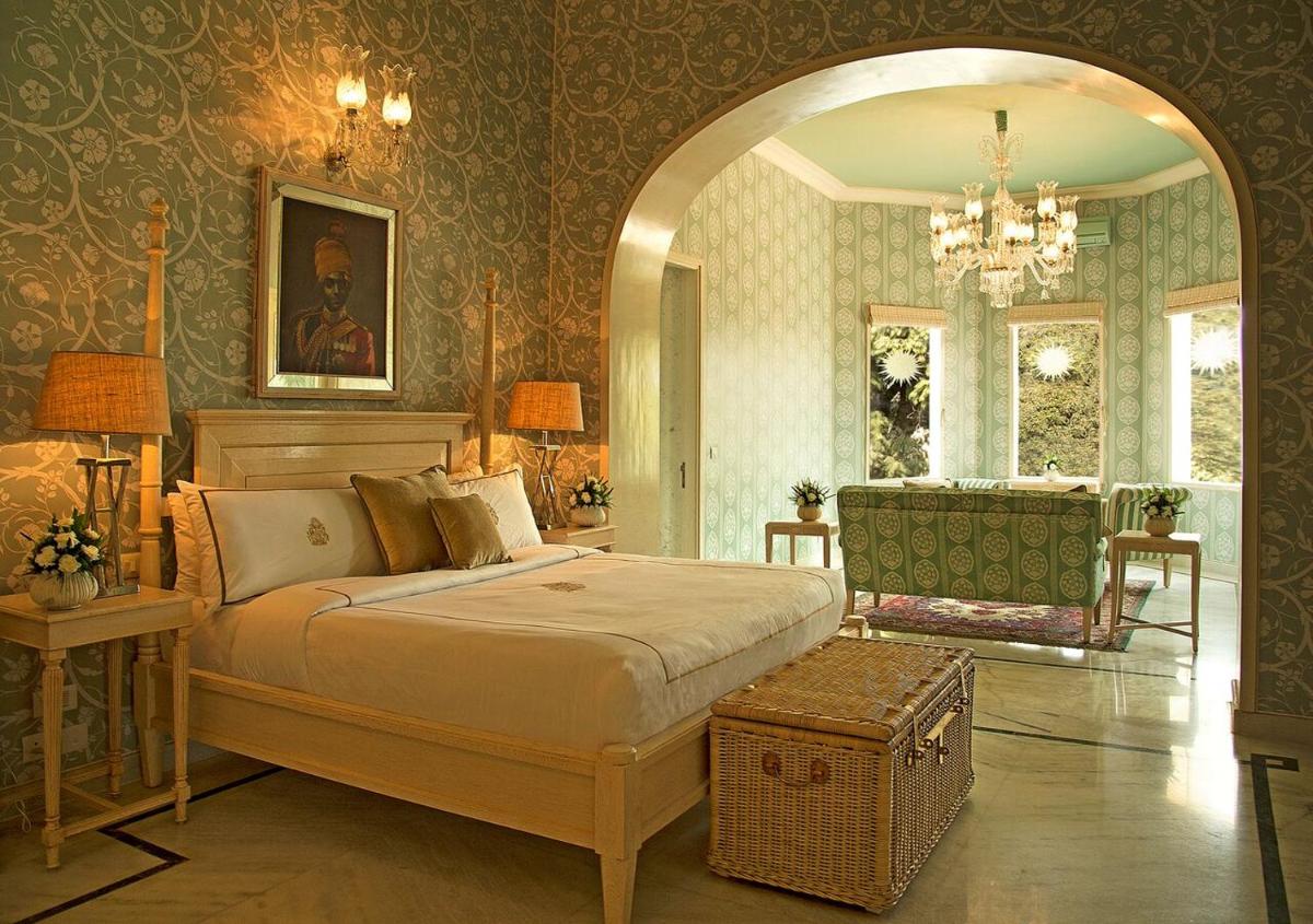 a bedroom with a large bed and a chair at Rajmahal Palace RAAS in Jaipur