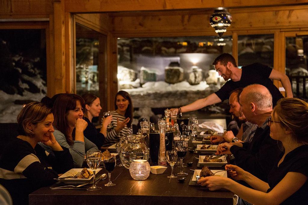 un groupe de personnes assises autour d'une table dans un restaurant dans l'établissement Hôtel et Chalet Au Coin Du Feu Chilly Powder, à Morzine