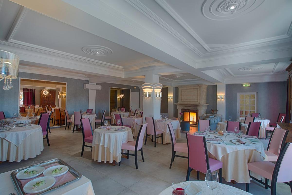 une salle à manger avec des tables blanches et des chaises roses dans l'établissement Logis Hôtel Restaurant Aux Maisons, à Maisons-lès-Chaource