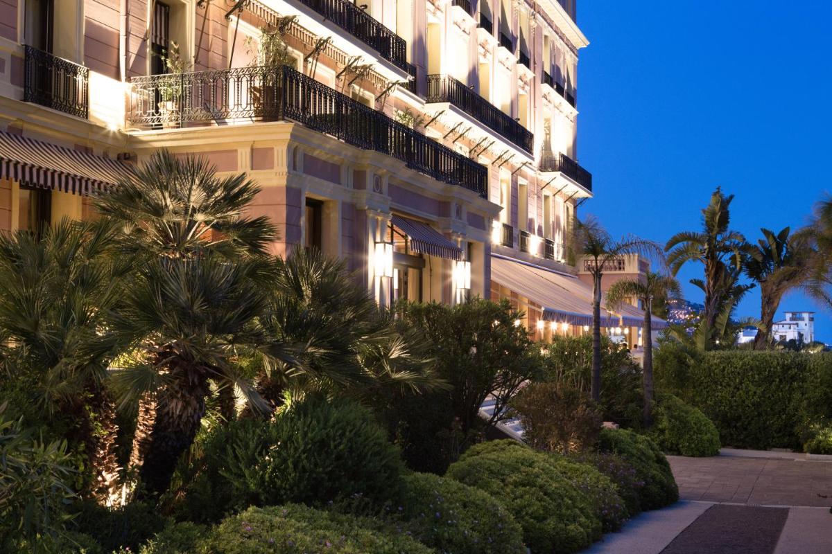 un grand bâtiment avec des palmiers devant dans l'établissement Hotel Royal-Riviera, à Saint-Jean-Cap-Ferrat