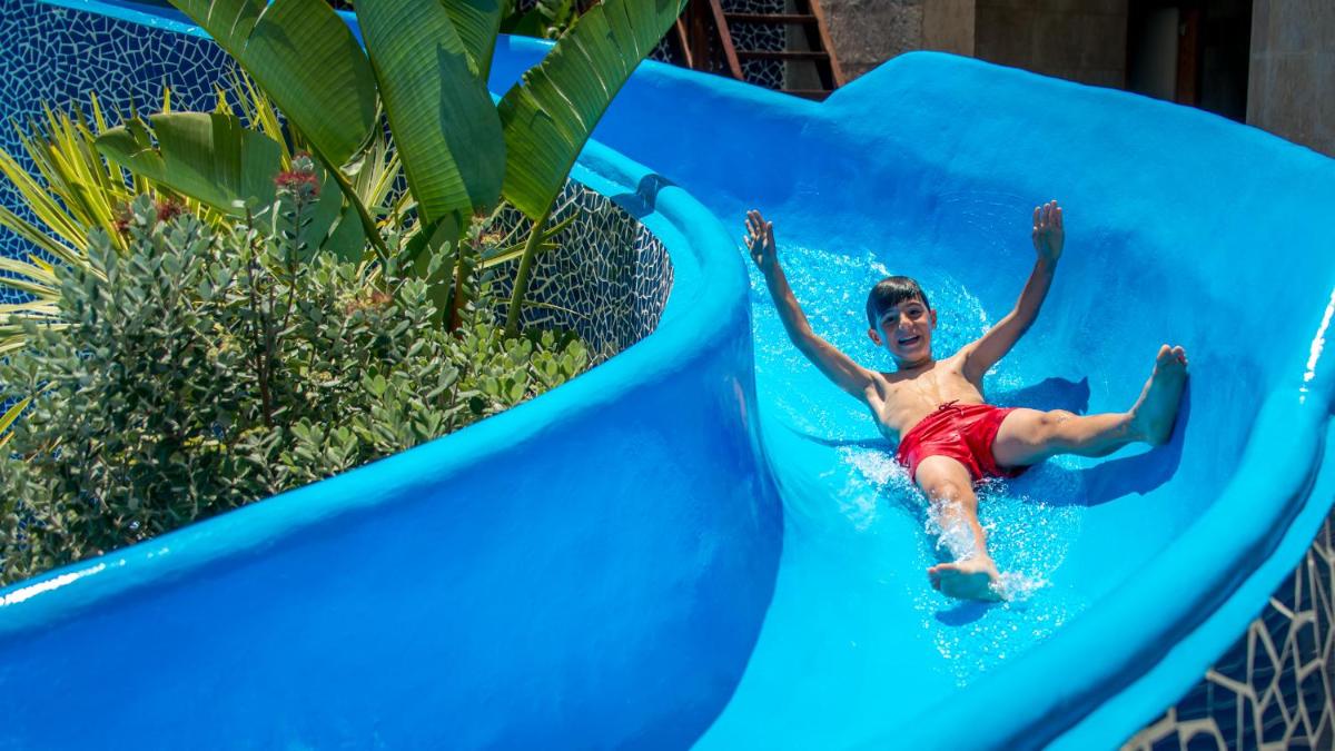 Un niño pequeño se desliza por un tobogán de agua en Hotel RH Vinaros Playa & Spa 4* Sup, en Vinarós