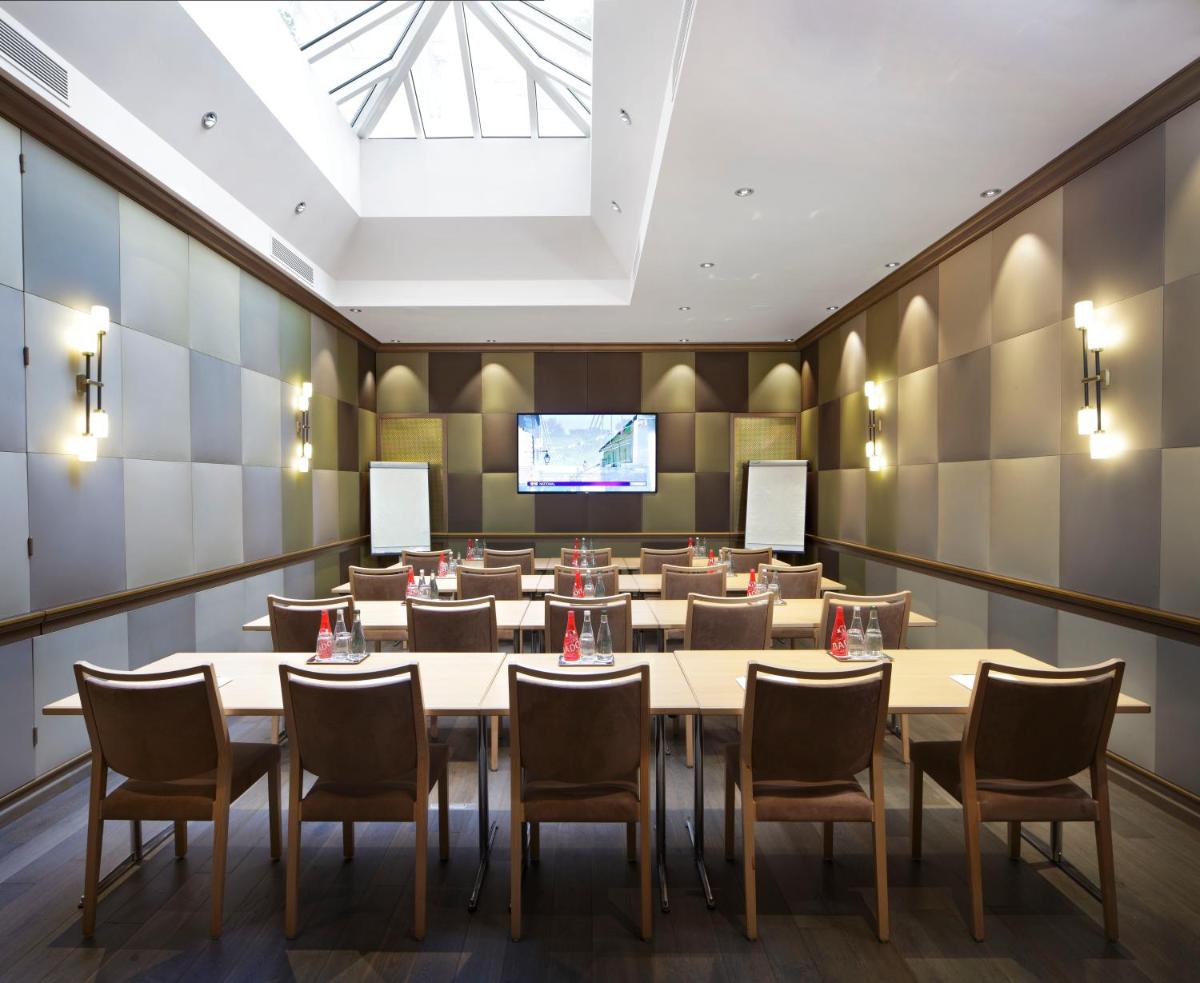 une grande salle avec des tables et des chaises et un écran de projection dans l'établissement Rochester Champs Elysees, à Paris