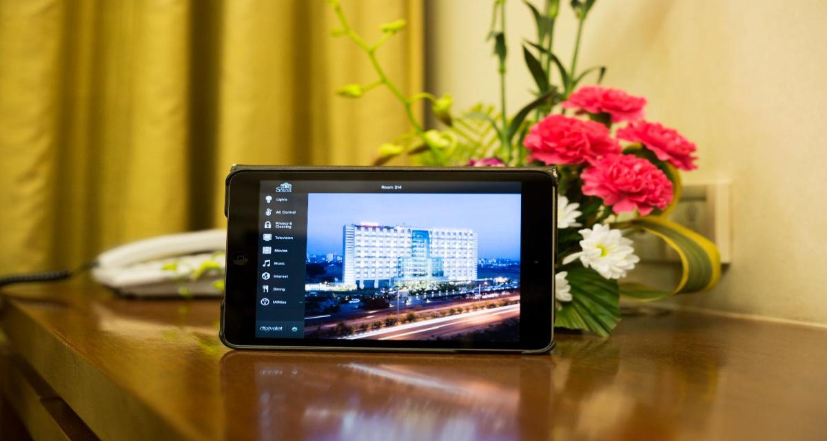 a tablet sitting on a table with a vase of flowers at Sayaji Pune in Pune