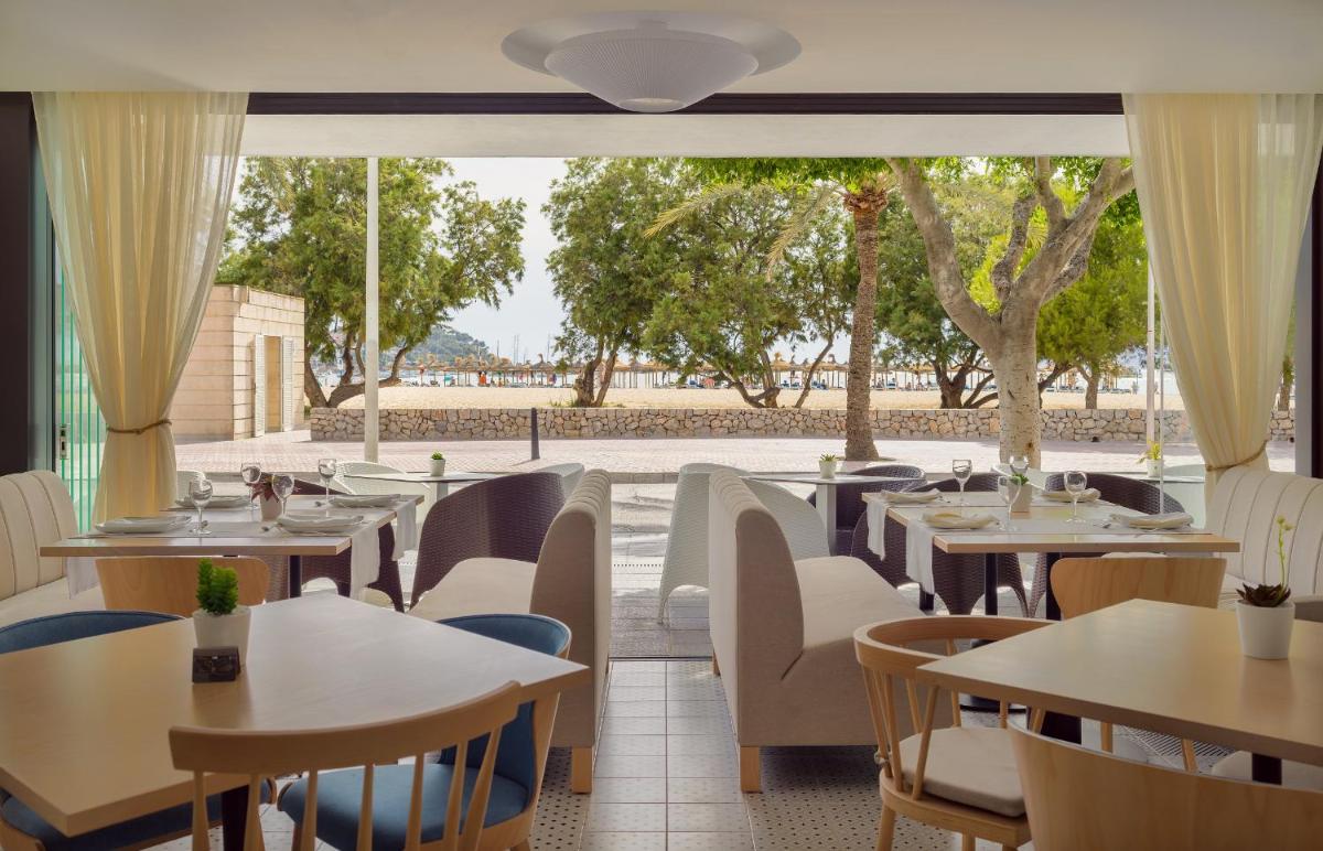 Un restaurante con mesas y sillas y un gran ventanal. en H10 Casa del Mar, en Santa Ponsa