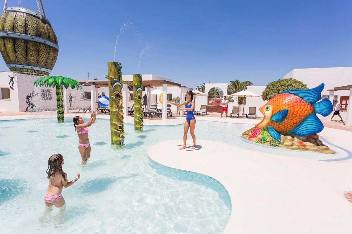 un grupo de niños jugando en una piscina en un parque acuático en Grand Palladium Select Palace Ibiza - All Inclusive, en Playa d'en Bossa