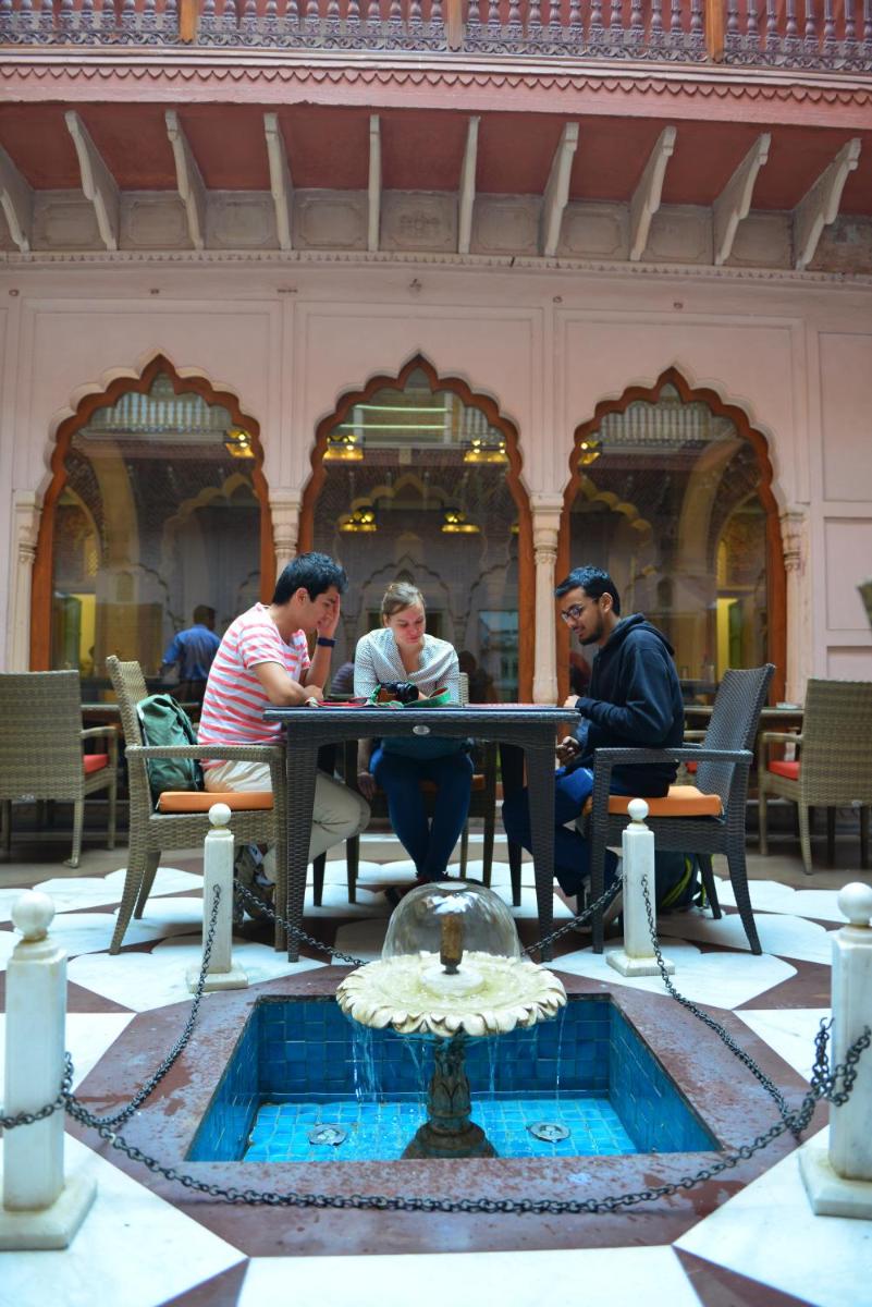 a group of people sitting at a table near a fountain at Haveli Dharampura & Golden Haveli- UNESCO awarded Boutique Heritage Hotel in New Delhi a group of people sitting at a table near a fountain at Haveli Dharampura & Golden Haveli- UNESCO awarded Boutique Heritage Hotel in New Delhi