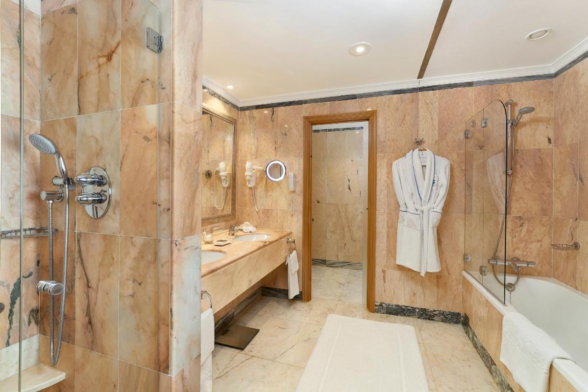 um banheiro com banheira, pia e chuveiro em Hotel Quinta do Lago na Quinta do Lago