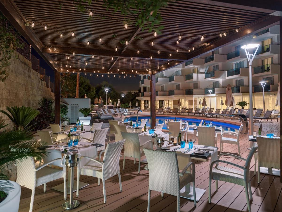 Un restaurante con mesas y sillas y una piscina. en Boutique Hotel H10 Blue Mar - Adults Only, en Camp de Mar