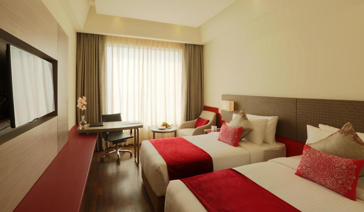 a hotel room with two beds and a desk at Ramada by Wyndham Lucknow Hotel and Convention Center in Lucknow