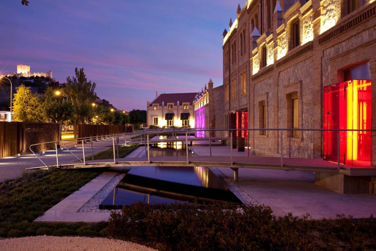 un puente sobre un río en una ciudad por la noche en Hotel AF Pesquera, en Peñafiel