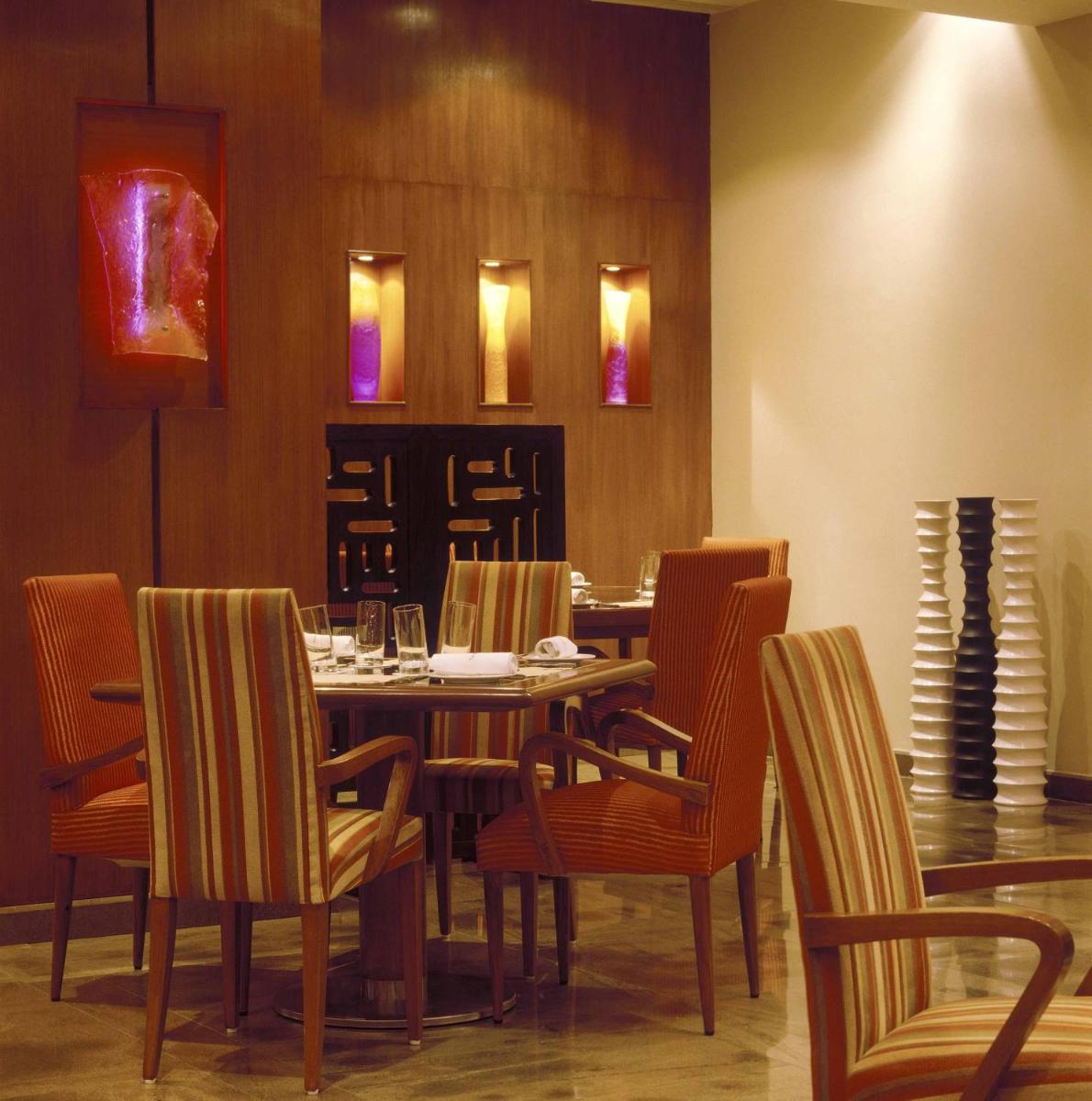 a dining room with a table and chairs at The Lalit Mumbai in Mumbai