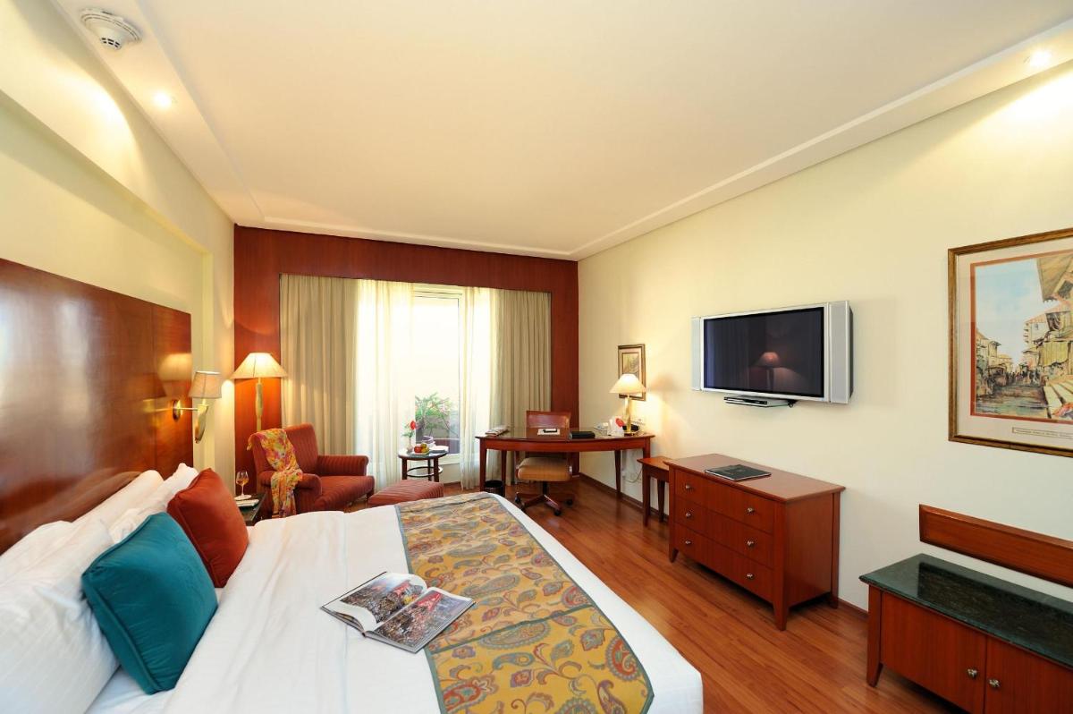 a hotel room with a bed and a television at The Lalit Mumbai in Mumbai