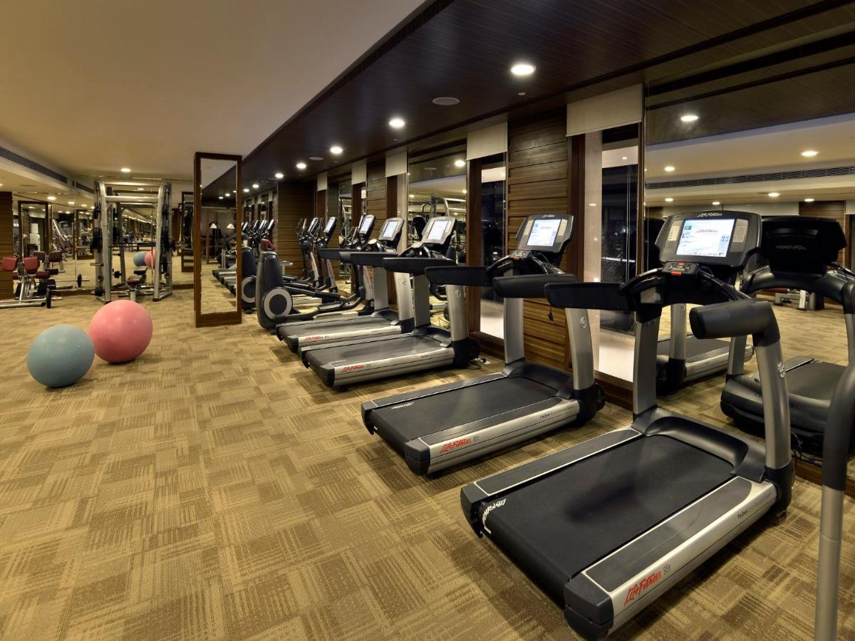 a gym with a row of treadmills and ellipticals at The Lalit Chandigarh in Chandīgarh