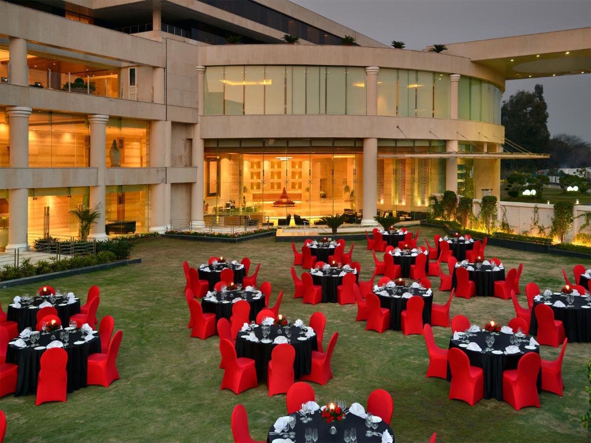 a resort with red chairs and tables in front of a building at The Lalit Chandigarh in Chandīgarh